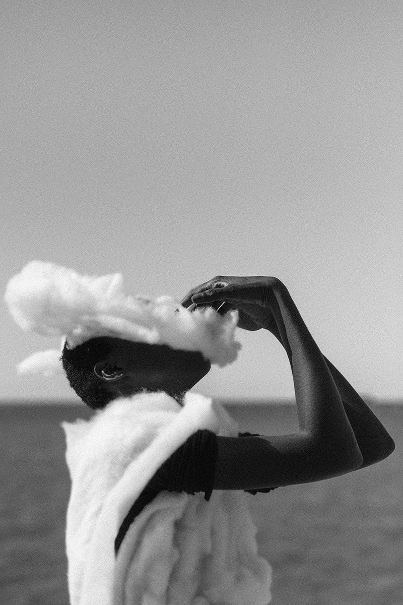 Black and white figure with face obscured by a cloud-like form