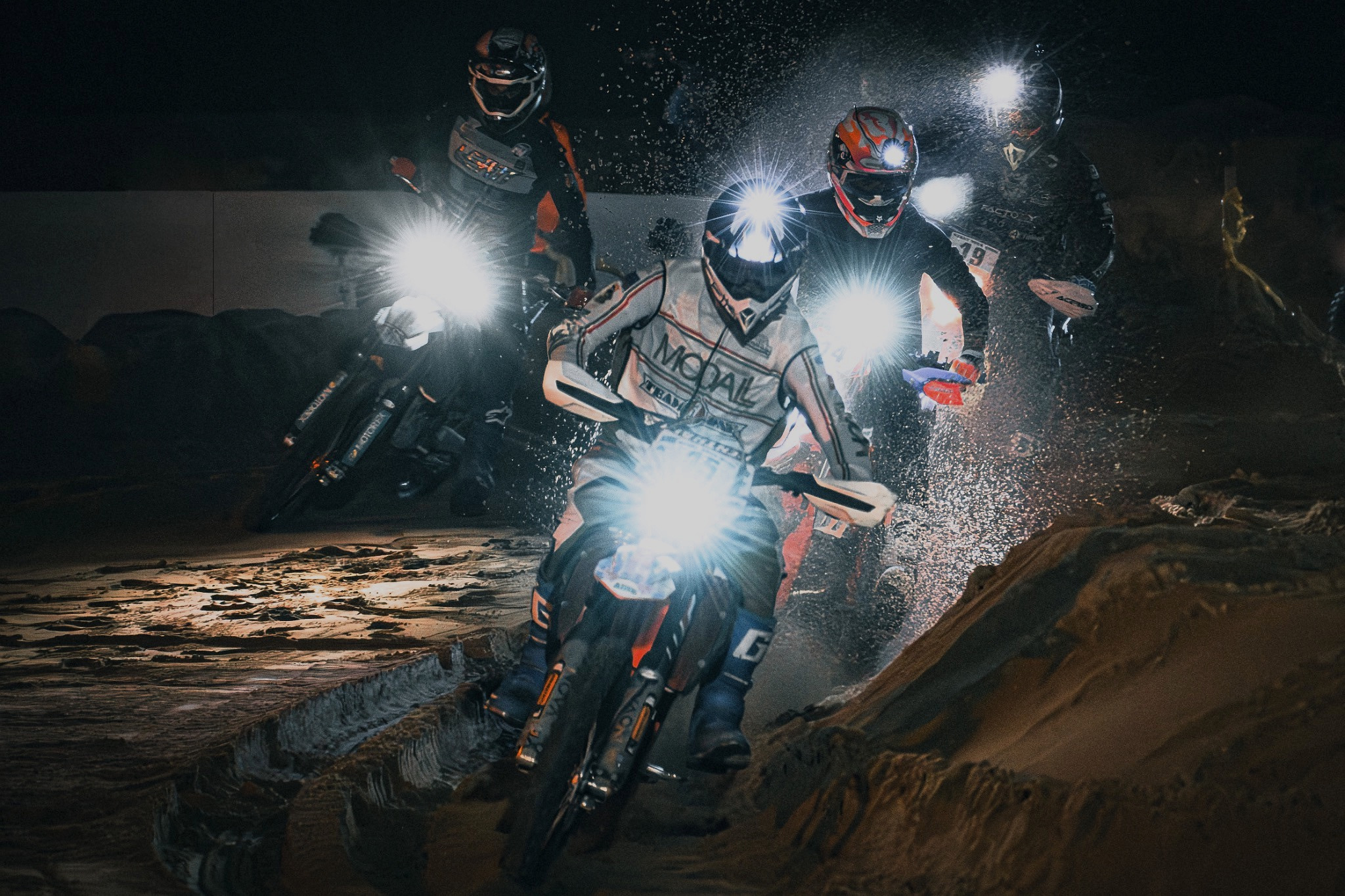 Motorcycle riders racing at night through water